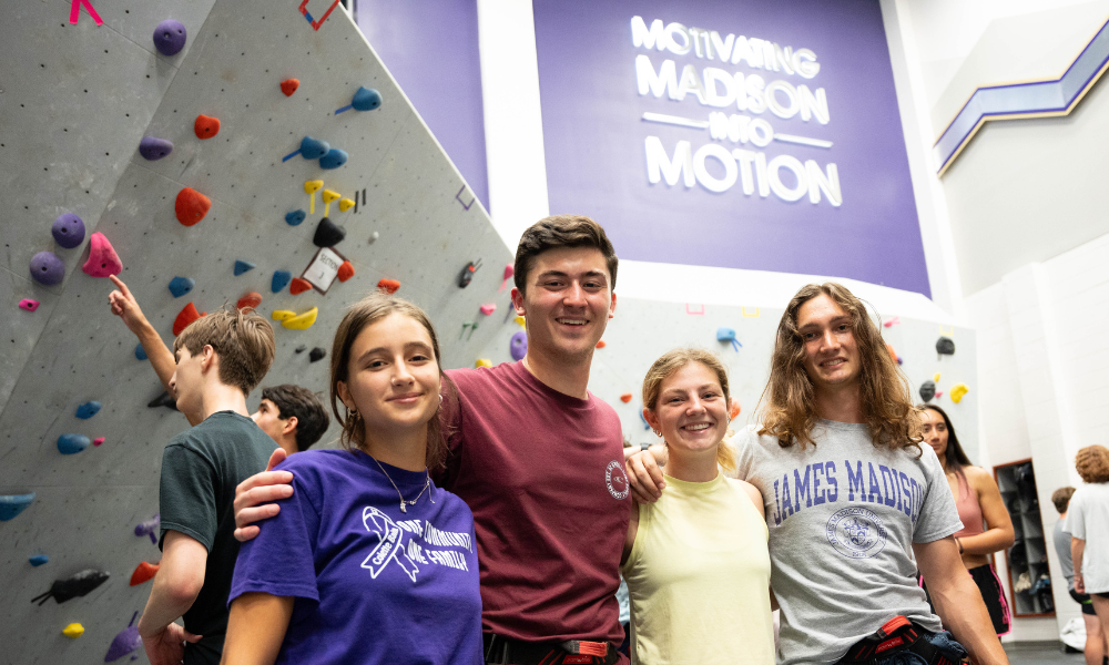 students posing in front of the bouldering wall