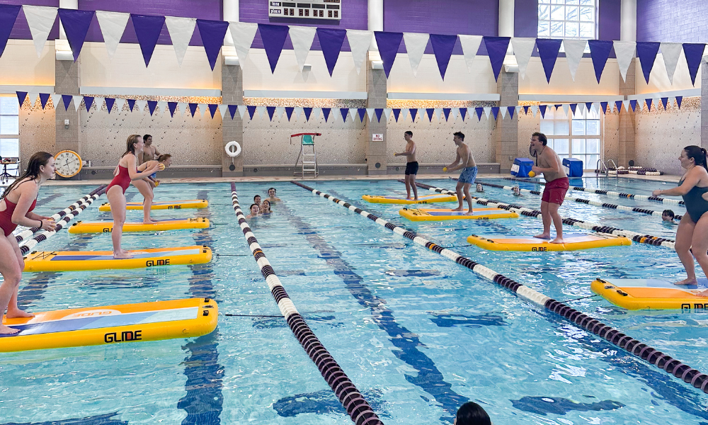 students playing dodgeball on stand up paddle board in the pool